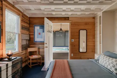 a bedroom with wooden walls and a bed and a window at 1930's Vintage Cabin Hot Tub Kohler Cabin in Jeffersonville