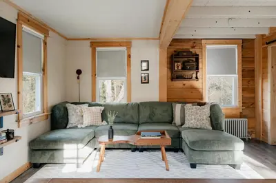 a living room with a green couch and a table at 1930's Vintage Cabin Hot Tub Kohler Cabin in Jeffersonville