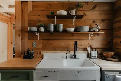 a kitchen with a sink and wooden walls at 1930's Vintage Cabin Hot Tub Kohler Cabin in Jeffersonville