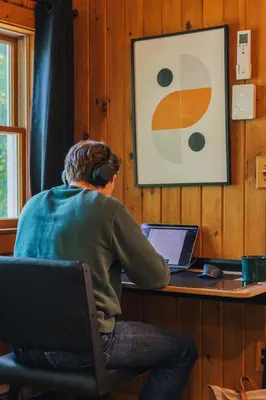 a man wearing headphones sitting at a desk with a laptop at Breathtaking River Views The Hawks Nest Cabin in Glen Spey