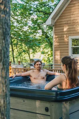 a man and a woman sitting in a hot tub at Breathtaking River Views The Hawks Nest Cabin in Glen Spey
