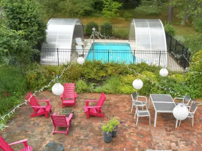 a patio with red chairs and a table and a pool at Catskill Rose Lodging & Dining in Mount Tremper