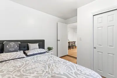 a bedroom with a bed and a white wall at Hamilton-15 mins to EWR, 20 mins PATH to NYC in Harrison