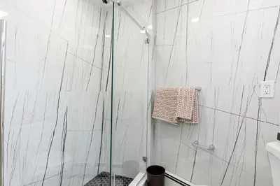 a shower with a glass door in a bathroom at Hamilton-15 mins to EWR, 20 mins PATH to NYC in Harrison