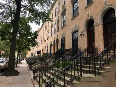 a brick building with stairs in front of a street at Modern Townhouse in Historic Harlem in New York