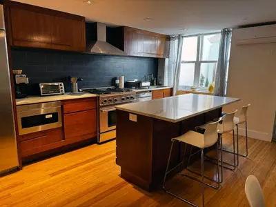 a kitchen with a stove and a counter with chairs at Modern Townhouse in Historic Harlem in New York