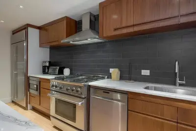a kitchen with stainless steel appliances and wooden cabinets at Modern Townhouse in Historic Harlem in New York