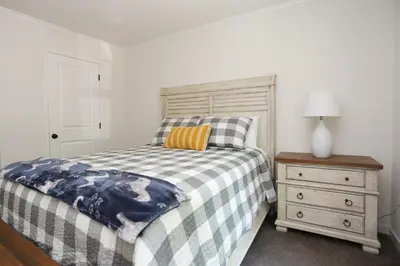 a bedroom with a bed with a checkered blanket and a night stand at Oneonta Hideaway in Oneonta