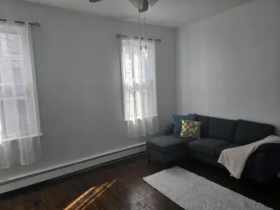 a living room with a couch and two windows at Cozy Getaway 2-Penn Station,NJPAC,Prudential Center in Kearny