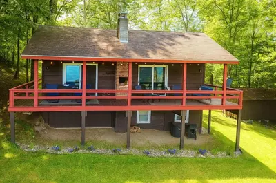a house with a large deck on the grass at Stunning Views from the Fire Tower Cabin in Cambridge