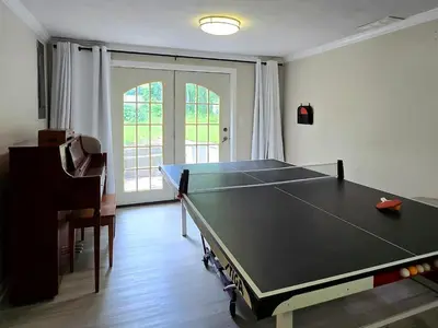 a ping pong table in a room with a ping pong ball at Spacious 4BR Retreat Yard, BBQ & Prime Location in Clifton Park