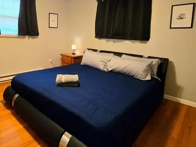 a bed with a blue comforter and two pillows at Spacious 4BR Retreat Yard, BBQ & Prime Location in Clifton Park