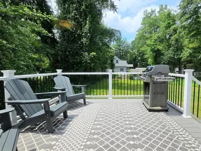 a patio with two chairs and a grill on a fence at Spacious 4BR Retreat Yard, BBQ & Prime Location in Clifton Park