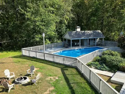 a swimming pool with a fence next to a house at Large Villa 5 Beds, 3 Baths, Firepit, Cozy Stay in Fort Edward