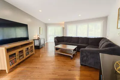 a living room with a couch and a flat screen tv at Large Villa 5 Beds, 3 Baths, Firepit, Cozy Stay in Fort Edward