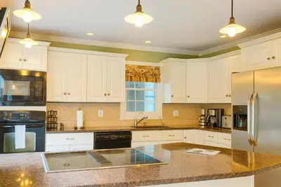a kitchen with white cabinets and a black refrigerator at Large Villa 5 Beds, 3 Baths, Firepit, Cozy Stay in Fort Edward