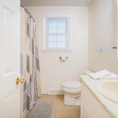 a white bathroom with a toilet and a window at Best house in town in Latham