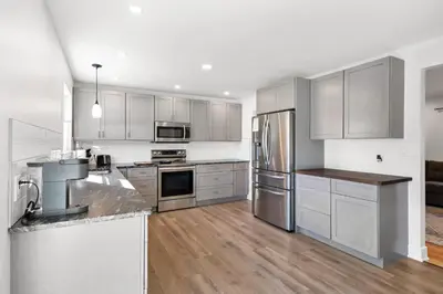 a kitchen with stainless steel appliances and wooden floors at Pet-Friendly Saratoga Home with Fire Pit & Deck in Saratoga Springs