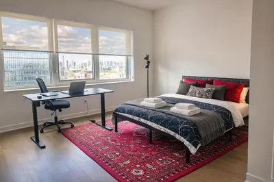 a bedroom with a bed and a desk with a laptop at Elegant Long Island City Studio with Skyline Views in Roosevelt Island