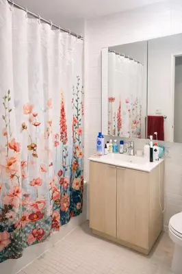 a bathroom with a shower curtain with a sink and a toilet at Elegant Long Island City Studio with Skyline Views in Roosevelt Island