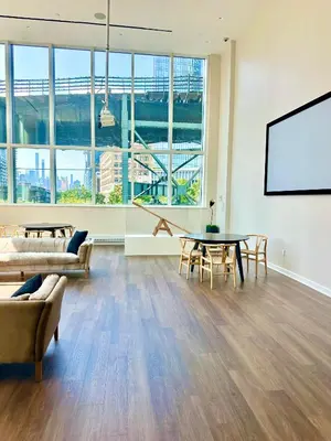 a living room with a table and chairs and a screen at Elegant Long Island City Studio with Skyline Views in Roosevelt Island
