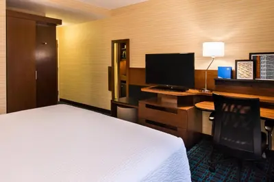 a hotel room with a bed and a desk with a computer at Fairfield Inn & Suites by Marriott Utica in Utica