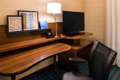 a desk with a computer monitor and a chair at Fairfield Inn & Suites by Marriott Utica in Utica