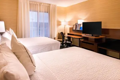 a hotel room with two beds and a desk with a computer at Fairfield Inn & Suites by Marriott Utica in Utica