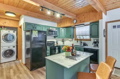 a kitchen with green cabinets and a counter top at 8 Mi to Mt Snow Cozy Bear Cabin with Hot Tub! in Wilmington