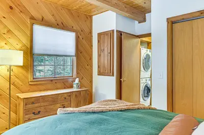 a bedroom with a bed and a washer and dryer at 8 Mi to Mt Snow Cozy Bear Cabin with Hot Tub! in Wilmington