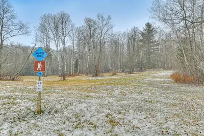 a sign on a snow covered road in a field at 8 Mi to Mt Snow Cozy Bear Cabin with Hot Tub! in Wilmington