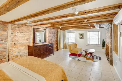 a bedroom with a brick wall and a bed and a table at Walk to Athens Riverfront Park! Modern-Retro Apt in Athens