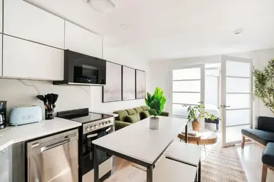 a kitchen and living room with white cabinets and a table at 22nd Sleek Modern 1BR Gramercy in New York