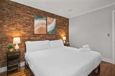 a bedroom with a white bed and a brick wall at Sleek Midtown East Stay Near Everything in New York