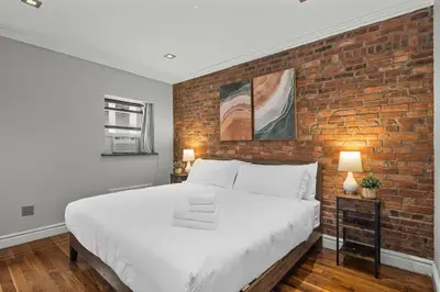 a bedroom with a brick wall and a large bed at Sleek Midtown East Stay Near Everything in New York
