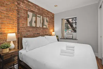 a bedroom with a white bed and a brick wall at Sleek Midtown East Stay Near Everything in New York