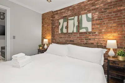 a bedroom with a white bed with a brick wall at Sleek Midtown East Stay Near Everything in New York