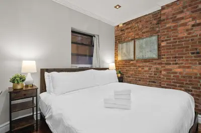 a bedroom with a white bed and a brick wall at Sleek Midtown East Stay Near Everything in New York