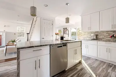 a kitchen with white cabinets and granite counter tops at Norwalk Retreat in Norwalk