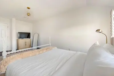 a white bedroom with a white bed and a tv at Norwalk Retreat in Norwalk