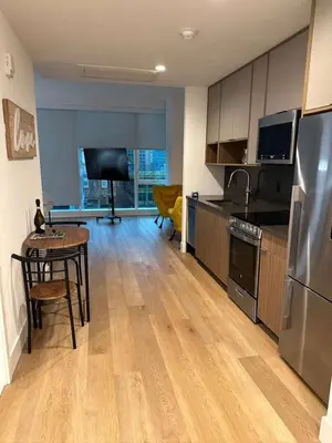 a kitchen with a table and a kitchen with a refrigerator at Bright, Modern Studio in White Plans in White Plains