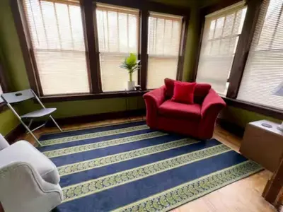 a living room with a red chair and a blue rug at NightShiftReady Binghamton Trades Nurses Welcome Private Room in Shared Apartment in Binghamton
