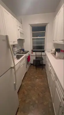 a small kitchen with white cabinets and a window at Holiday Glow Apartments in Rego Park
