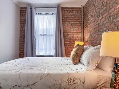 a bedroom with a bed and a brick wall at Suite 45 - East Harlem, Manhattan by Monthier in New York