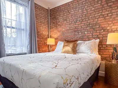 a bedroom with a brick wall and a bed with pillows at Suite 45 - East Harlem, Manhattan by Monthier in New York