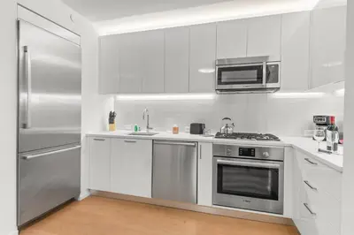 a white kitchen with a stainless steel refrigerator and microwave at 685 First Ave in New York