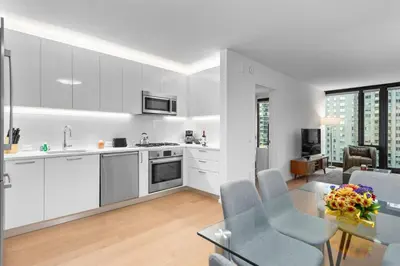 a kitchen with white cabinets and a glass table at 685 First Ave in New York