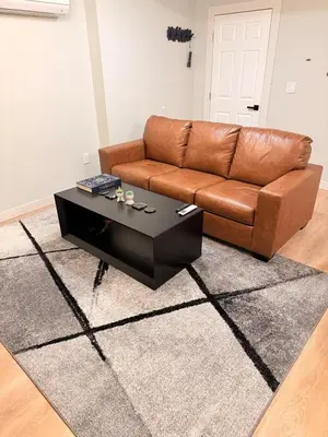 a living room with a brown couch and a coffee table at Huge Private Suite with Pool Table, Sauna & Fire Pit in Ellenville