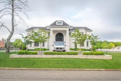 a white house with a truck parked in the driveway at Luxury 4BR Magical Oasis Villa Mansion with Indoor Basketball Court and Gym in Melville