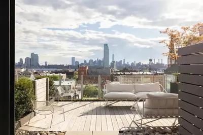 a balcony with a couch and a view of a city at Beautiful Modern Studio in Luxury Building in Brooklyn